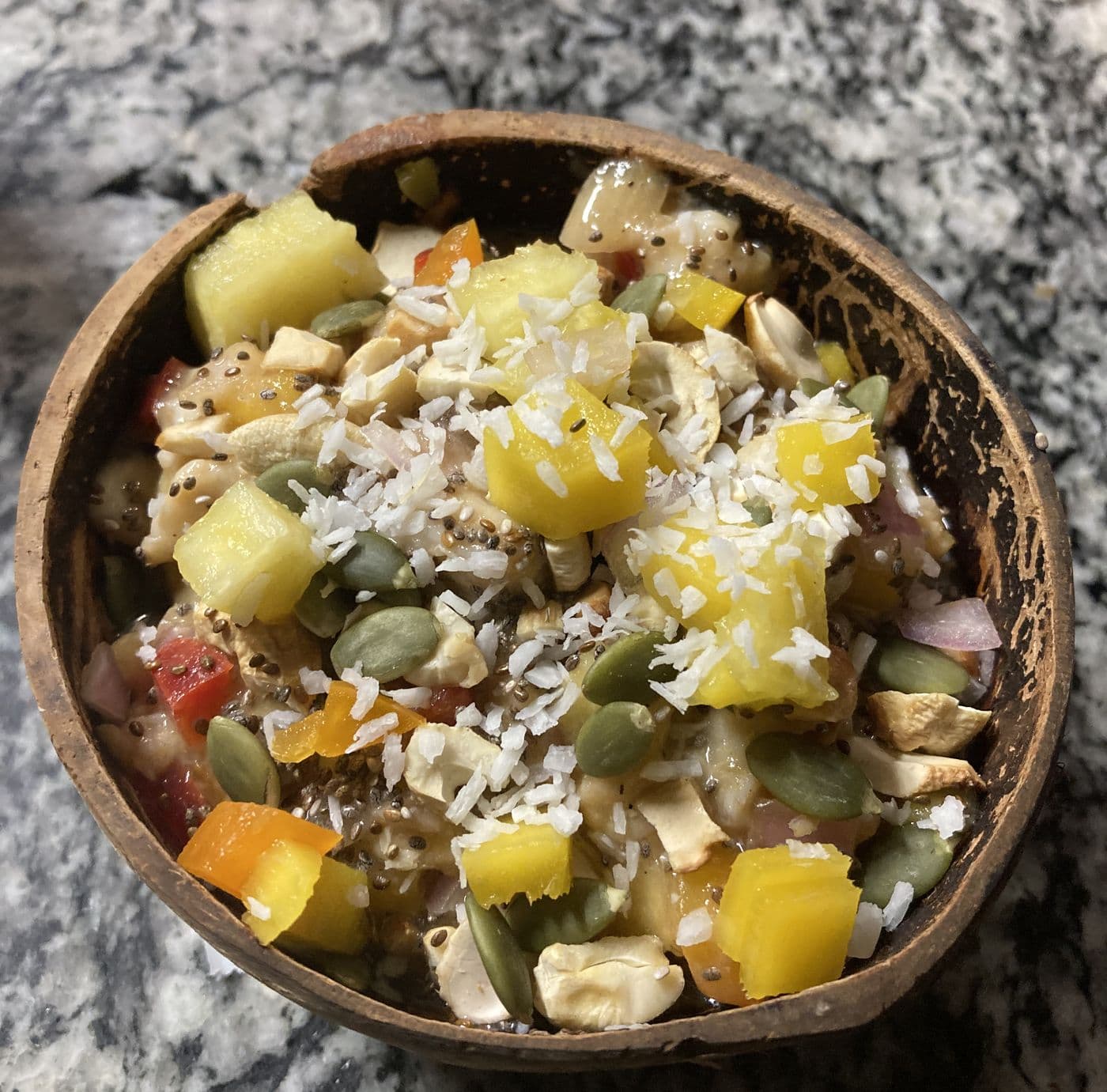 A tropical fruit and nut salad served in a coconut shell.